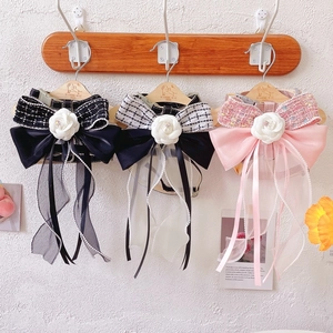 Detailed view of tweed pet harnesses with silk bows, pearls and camellia flowers