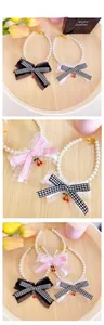 Detail of pet pearl collar with lace bow and cherry pendant in various colors