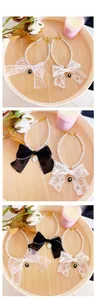 Detail of pet pearl necklace set with lace bows and vintage rose pendants on wood