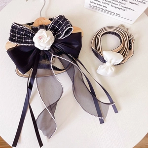 Detail of dog harness with black bow, white camellia flower and lace ribbon accents