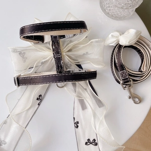 Detail of pet harness with white organza bow and matching leash on white background