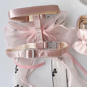 Detailed view of pink satin dog harness featuring organza bow and adjustable buckle strap