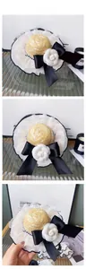 Detail of luxury pet straw hat with white lace trim, camellia flower and black bow