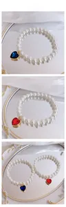 Detail of elegant pearl pet necklace with heart-shaped blue and red crystal pendants