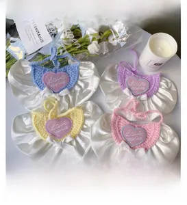 Close-up of crochet pet bibs with heart embroidery, satin ruffles and white bows