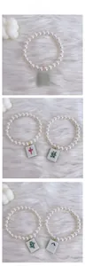 Detail of pet pearl necklace with Mahjong tiles on white plush background