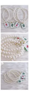 Close-up of pearl pet necklace with golden Mahjong tiles on white plush background