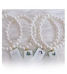Detailed view of pearl pet necklaces featuring miniature mahjong tile charms