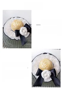 Detailed view of pet straw hat featuring white mesh trim, black bow, and camellia flower