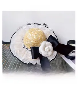 Detail of pet straw hat featuring a white camellia flower, black bow and lace trim