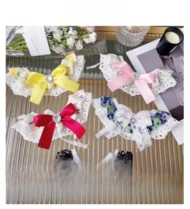 Detail view of five floral lace pet collars with large satin bows and rhinestone hearts