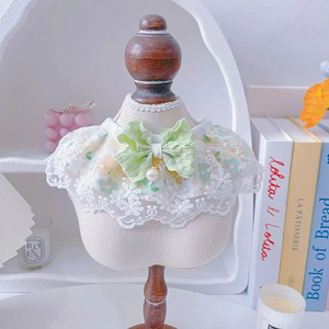 Detail of floral pet lace collar with green bow and pearl pendant on a mini mannequin
