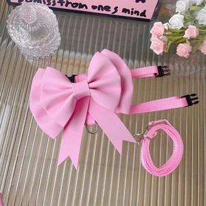 Pink pet harness set with large bow and nylon leash on a stylish modern glass background
