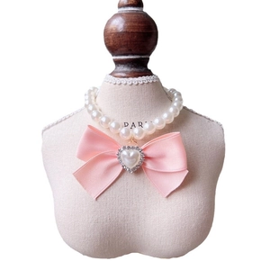 Elegant white pearl pet necklace with pink satin bow and rhinestone heart pendant on display