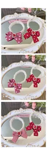 Detail of pearl pet necklaces with red ribbon bows and heart gemstone pendants