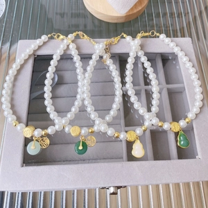 Detail of pet pearl necklaces with traditional Chinese jade-like charms in a jewelry box