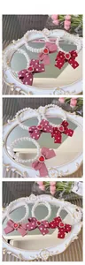 Detailed close-up of pearl pet necklaces with three different red bow patterns and heart gems