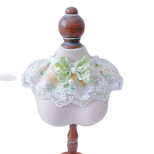 Lace pet collar with floral patterns and a green bow on a miniature dress form