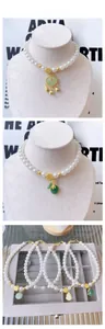 Detail of Chinese style pet pearl necklace with gold pendants and jade-like charms