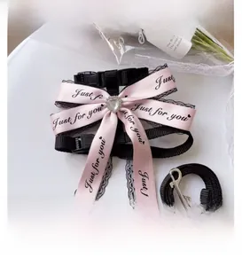 Close-up of pink ribbon bow with heart gem on black lace pet harness and leash set