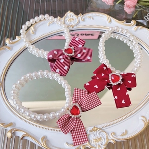 Elegant pearl pet necklace with red bow and rhinestone heart on vintage mirror