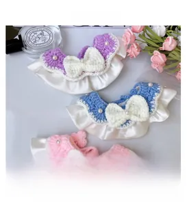Detail of crochet pet bibs with lace edges, pearls and bows in pastel colors