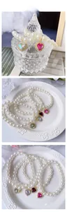 Detailed view of pearl necklaces with heart-shaped crystal pendants in multiple colors