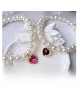 Detail of handmade cat pearl necklace with heart-shaped gemstone pendant and gold trim