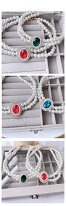 Close-up of double-layer pet pearl necklace with colorful gemstone pendants in a jewelry box