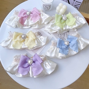 Close-up of cream pet collars with colorful bows and heart pearls on a white tray