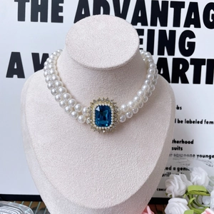 Double-layer pearl pet necklace with a large blue gemstone and sparkling diamonds