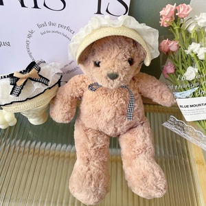 Detail of pink teddy bear wearing a lace woven straw hat with black and white bow tie