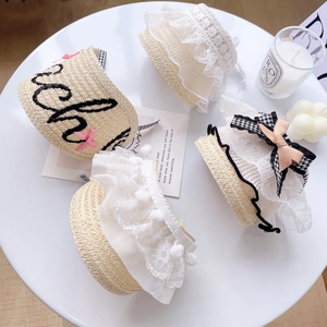 Straw pet hats with white lace edges, embroidery and pink silk bows on a white table