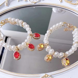 Detail of elegant pet pearl necklaces with red and yellow gemstone pendants and crystals