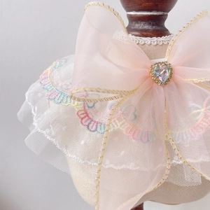 Close-up of pink mesh bow pet collar with rainbow lace and heart-shaped gemstone