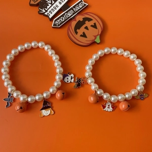 Halloween pet pearl necklace with pumpkin bell and ghost charms on orange background