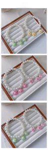Detail of pearl pet necklaces featuring macaron resin flower charms on a wooden display
