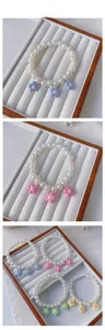 Detail view of handmade pearl pet necklaces with colorful floral charms for cats and dogs