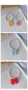 Detail view of pearl pet necklaces with resin bows in yellow, pink, blue, and red colors