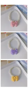 Three-tier display of pet pearl necklaces with cute bow charms in pink, purple, and yellow