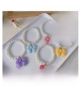 Detailed view of handmade pet pearl necklaces with colorful bows on a white tray