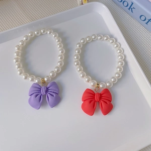 Cute pet pearl necklace featuring matte purple and red bows for cats and small dogs