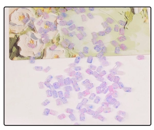 Macro detail of triangle glass beads for DIY jewelry making in purple and pink tones