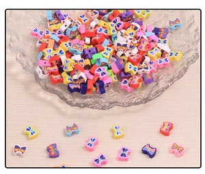 Close-up of colorful polymer clay butterfly beads for DIY jewelry making in a glass dish