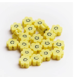 Gros plan de perles florales jaunes en pâte polymère avec smileys pour bijoux DIY