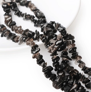 Polished irregular black natural stone beads in a white ceramic dish for DIY jewelry crafts