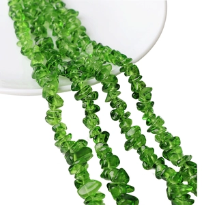 Close-up of irregular emerald green glass beads for DIY jewelry making on white ceramic