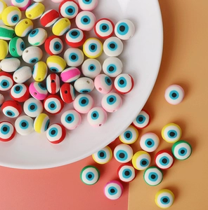Perles colorées œil protecteur en pâte polymère pour bijoux DIY sur une assiette blanche