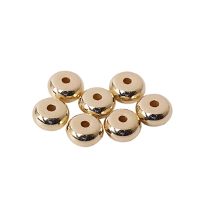 Close-up of seven polished gold-tone donut-shaped spacer beads with a smooth metal finish