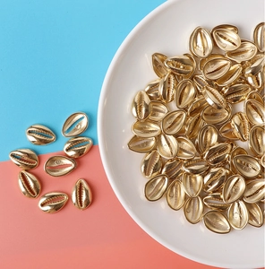 Golden shell CCB beads for DIY jewelry making displayed in a white ceramic tray